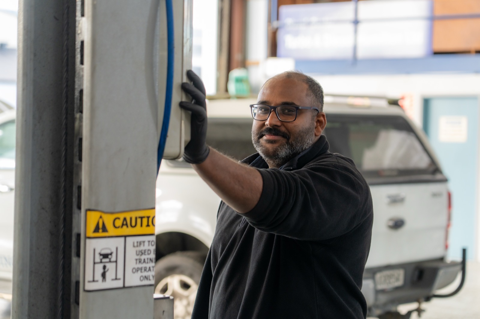 Turbo & Diesel technician operating the hoist controls with a white ute raised in our Frankton workshop.