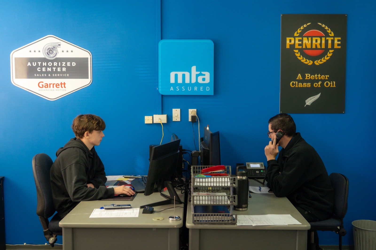 The Turbo & Diesel front desk team at work beneath the Garrett Authorized Center and MTA Assured signage.
