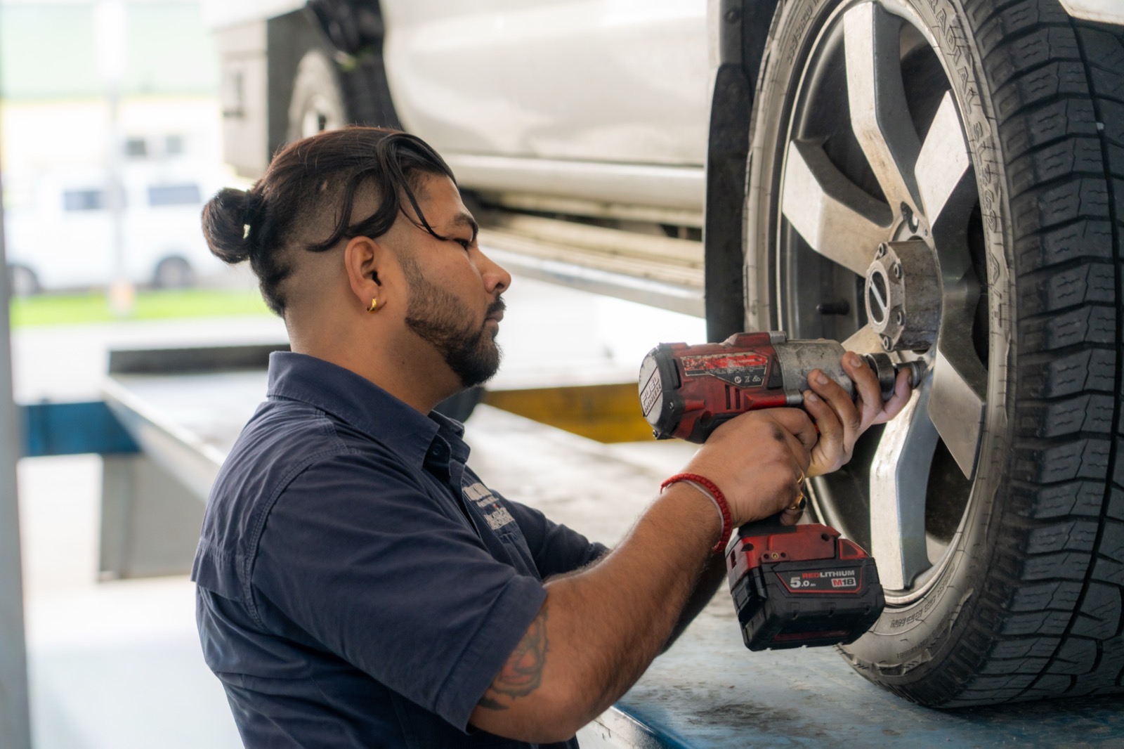 Close-up of a technician using an impact wrench on a wheel with the vehicle raised on the hoist.